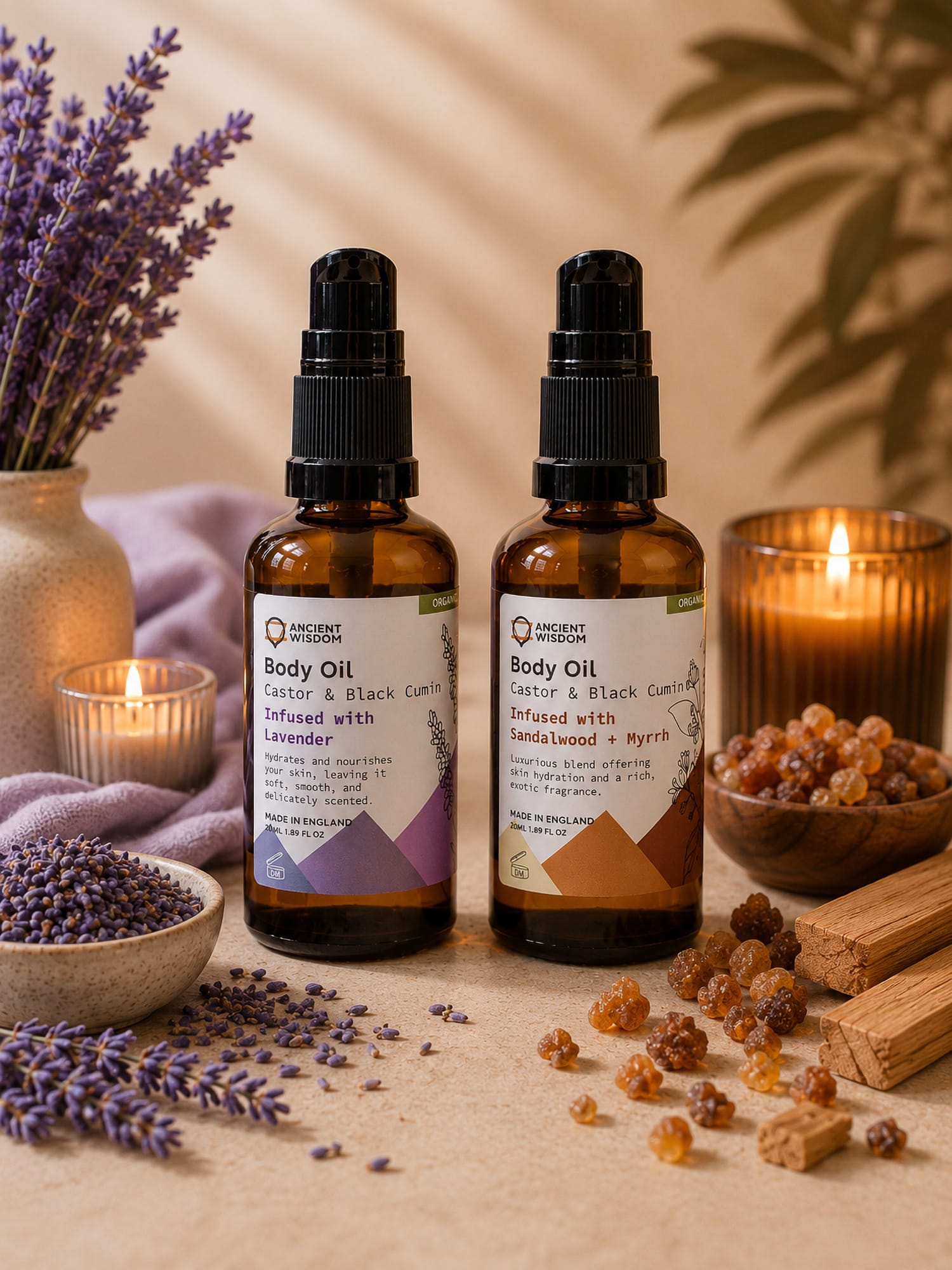 Sandalwood & Myrrh and Lavender body oil bottles displayed with dried lavender, resin pieces and a lit candle.