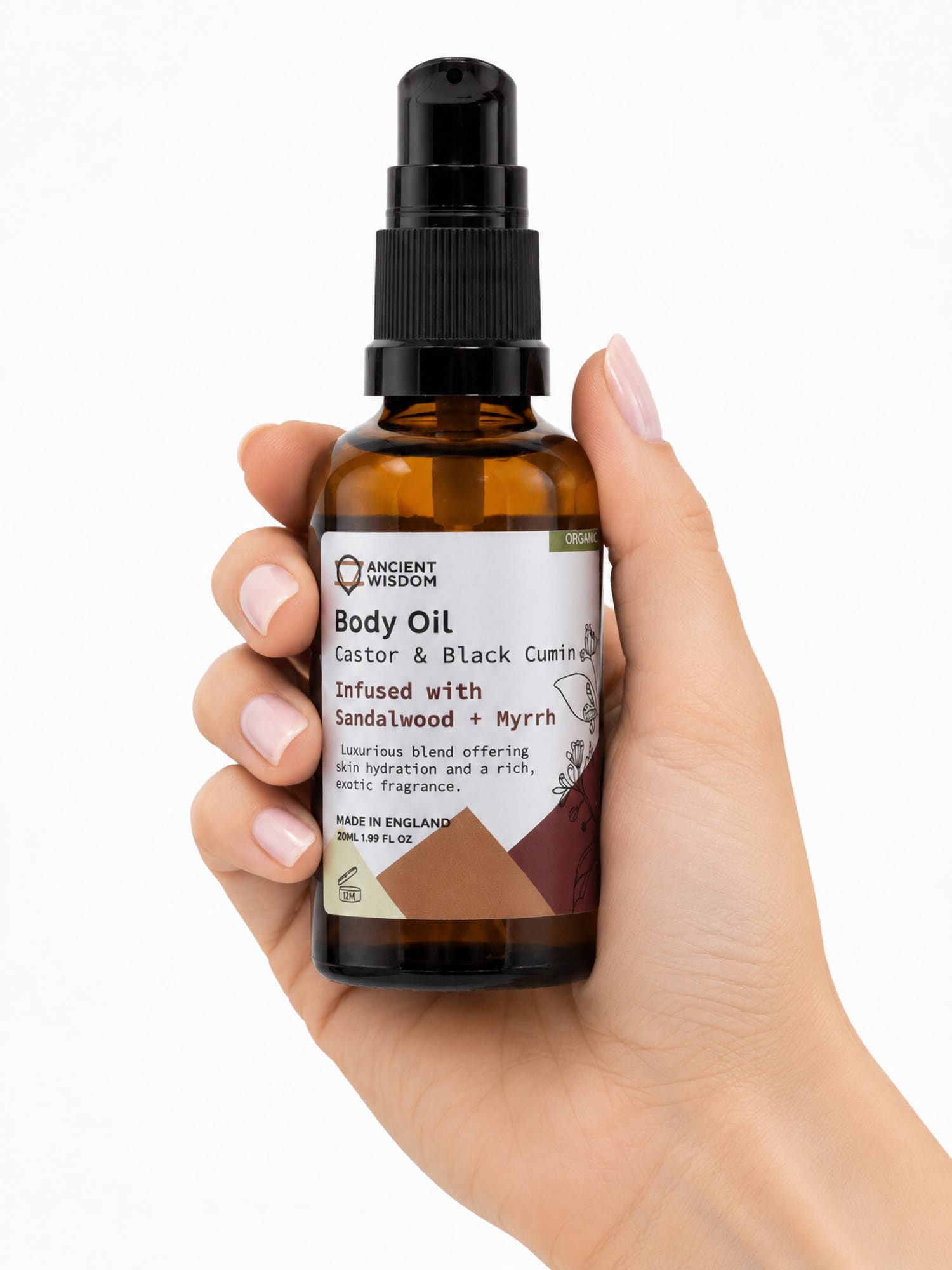 Hand holding amber Sandalwood & Myrrh body oil bottle with black pump and brown label accents.