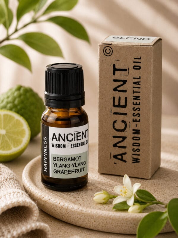 Happiness essential oil bottle with black cap beside kraft box, lime, leaves and white blossom on beige tray.