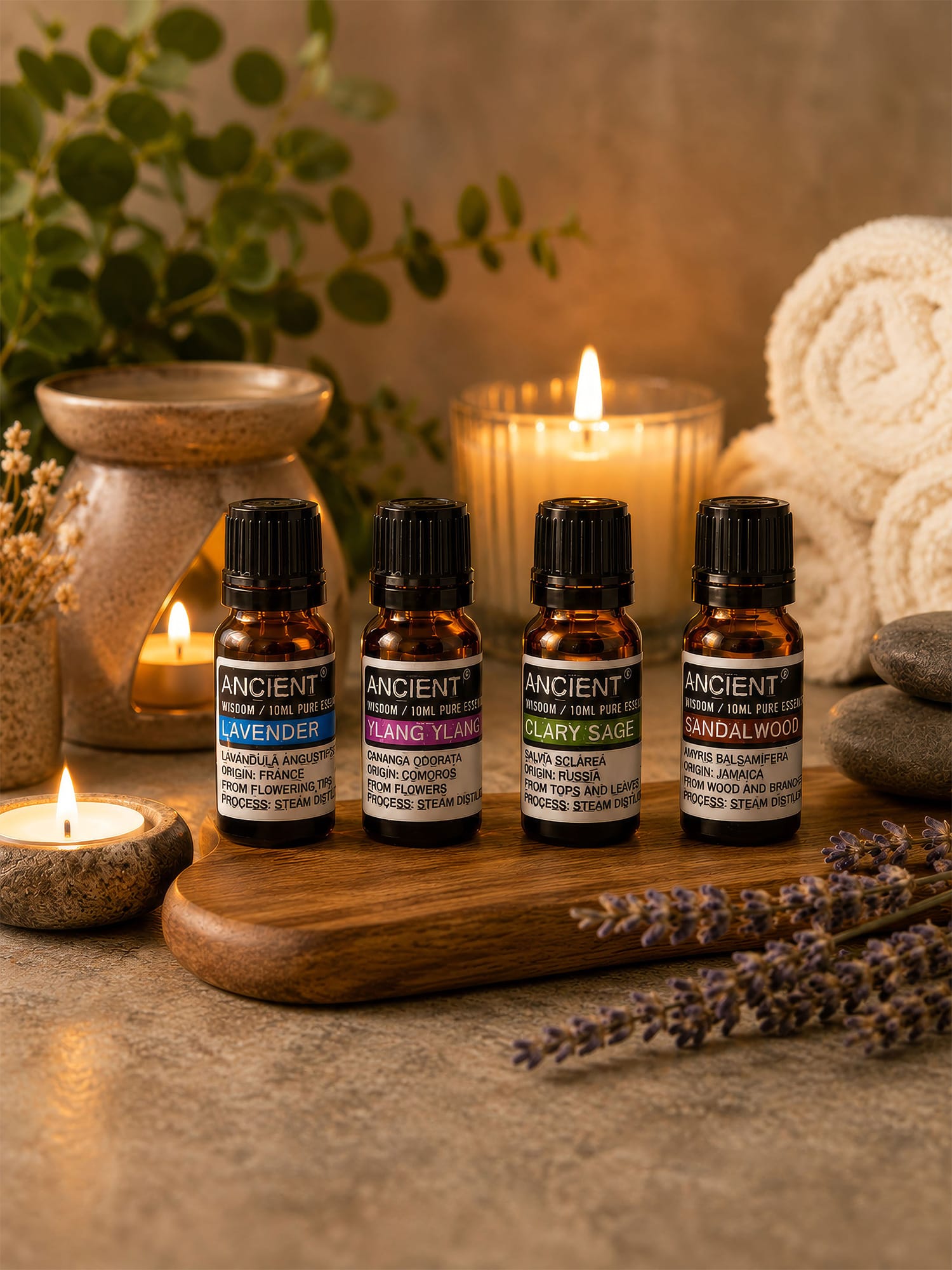 French Lavender essential oil shown with Ylang Ylang, Clary Sage and Sandalwood oils on tray with candles and towels.