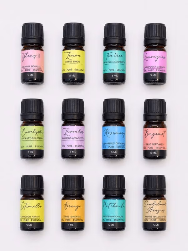 Set of 12 small amber essential oil bottles with black caps and colourful labels arranged in a neat grid.
