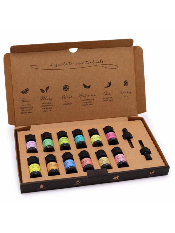 Open aromatherapy gift box showing 12 colourful essential oil bottles and two droppers with printed guide inside the lid.