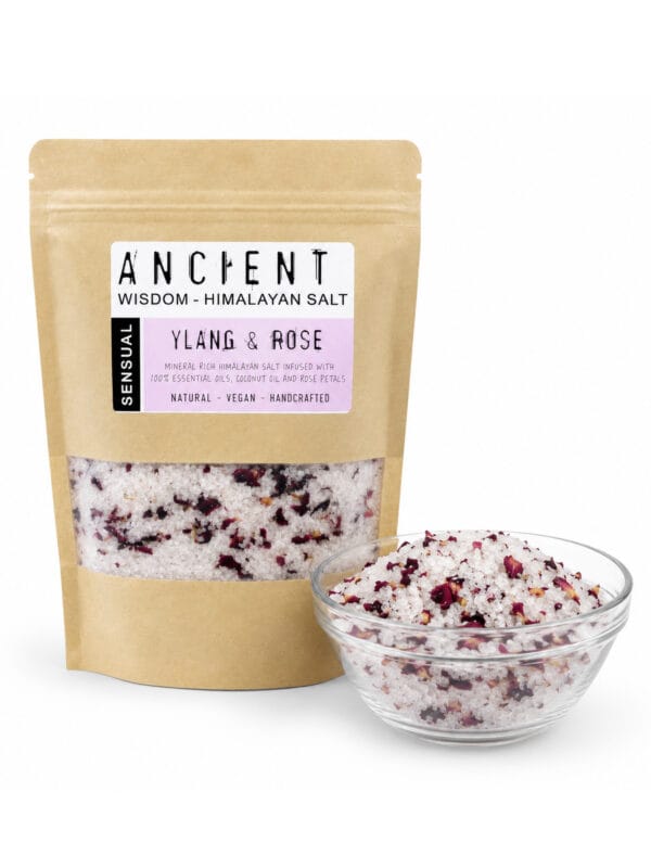 Sensual Rose & Ylang Ylang bath salts pouch beside glass bowl of salt and rose petals.