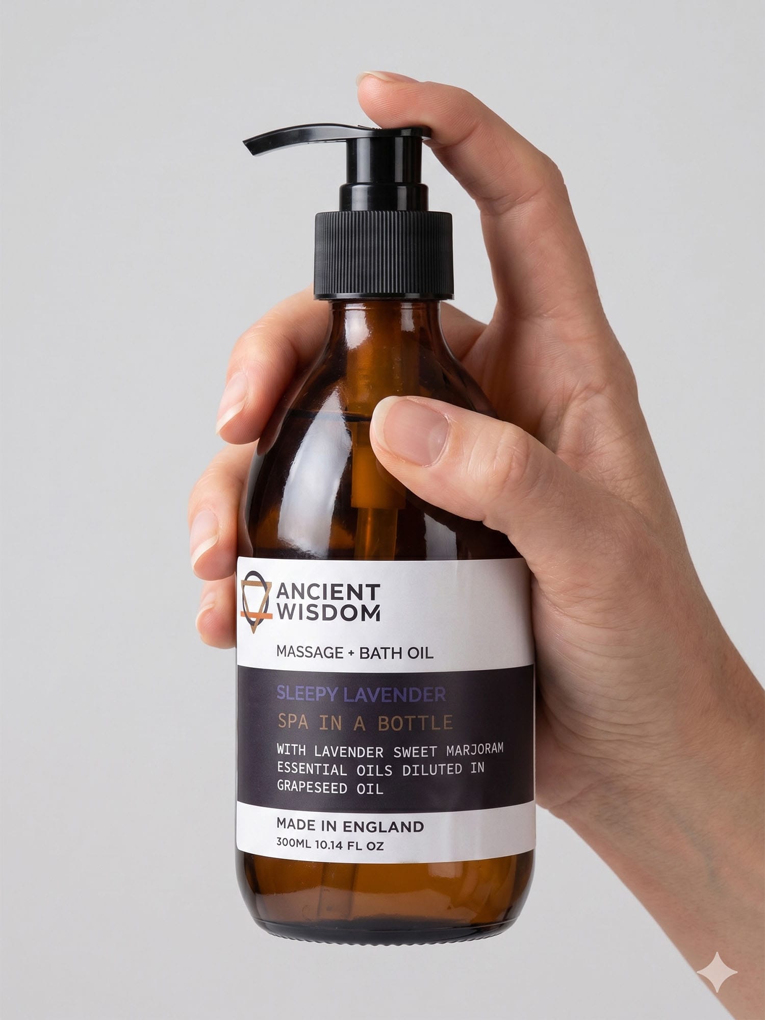 Hand holding Sleepy Lavender Massage & Bath Oil pump bottle, fingers on the black pump top.