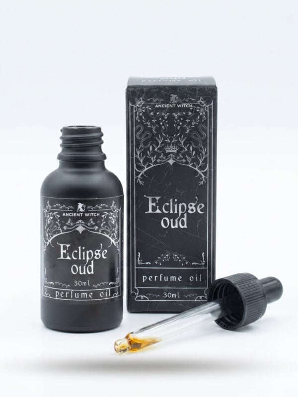 Open Eclipse oud perfume oil bottle with dropper pipette showing golden oil and ornate box behind.