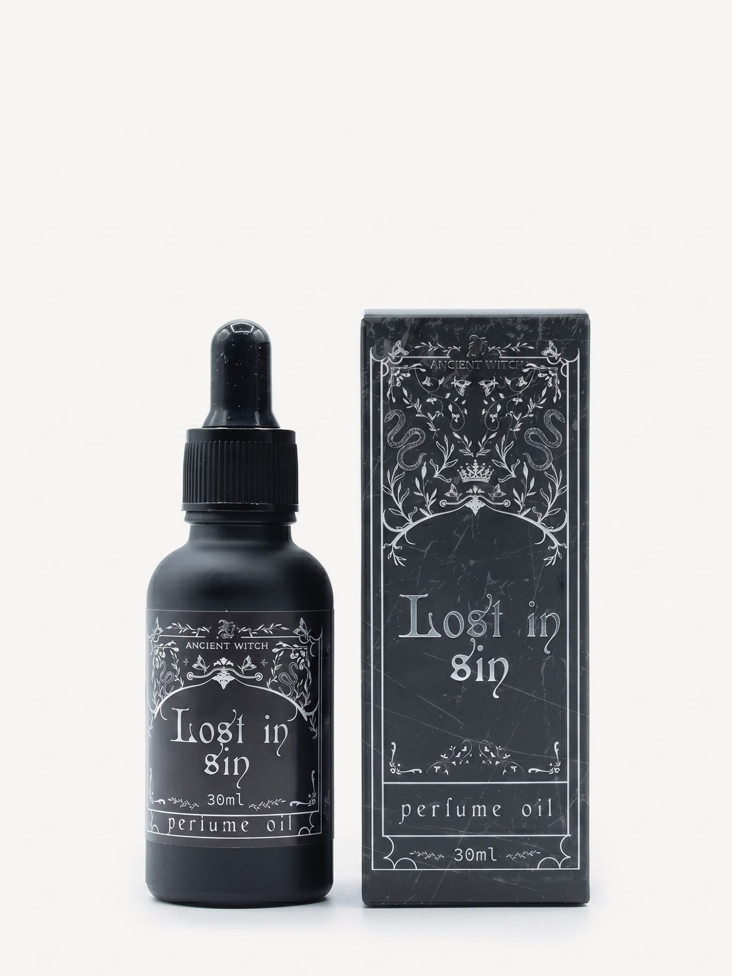 Lost in Sin perfume oil bottle with dropper next to matching ornate black box.