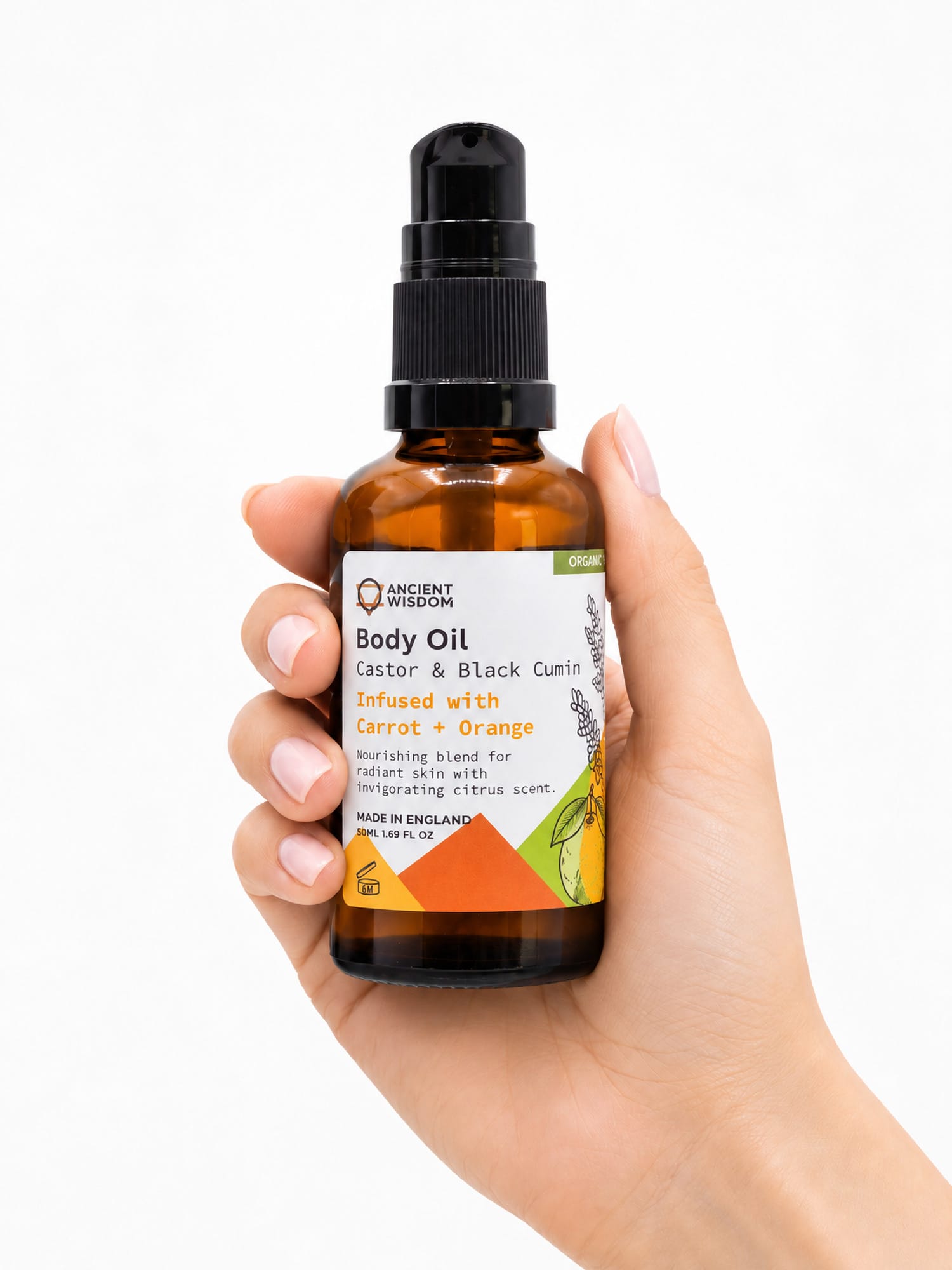 Hand holding the 50ml amber pump bottle of Ancient Wisdom Carrot & Orange Organic Body Oil against a white background.