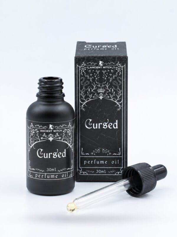 Open 30ml bottle of Cursed perfume oil with its glass dropper and black presentation box on a white background.