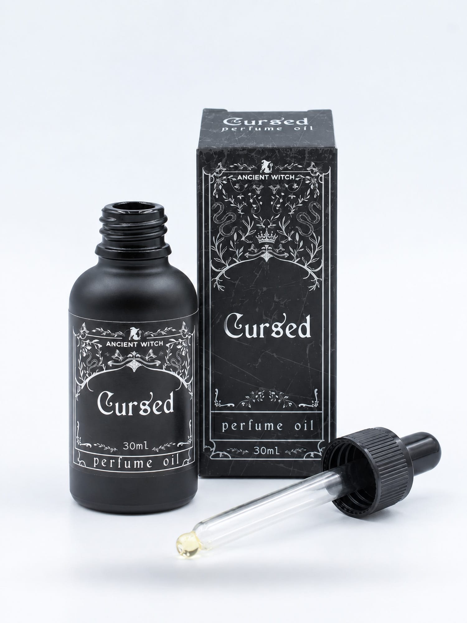 Open 30ml bottle of Cursed perfume oil with its glass dropper and black presentation box on a white background.