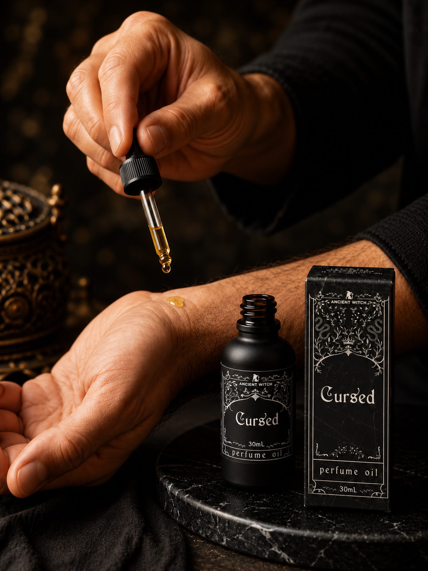 A drop of Cursed perfume oil being applied to a wrist beside the open 30ml bottle and presentation box.